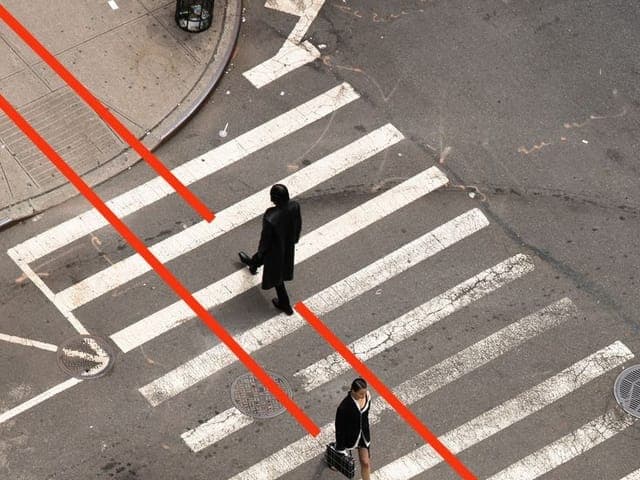 Aerial view of people crossing a city intersection, their paths traced in red