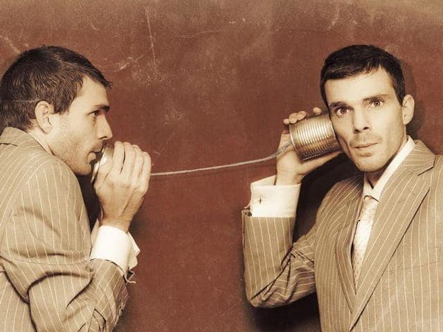 Two businessmen talking through a tin-can telephone, vintage photograph