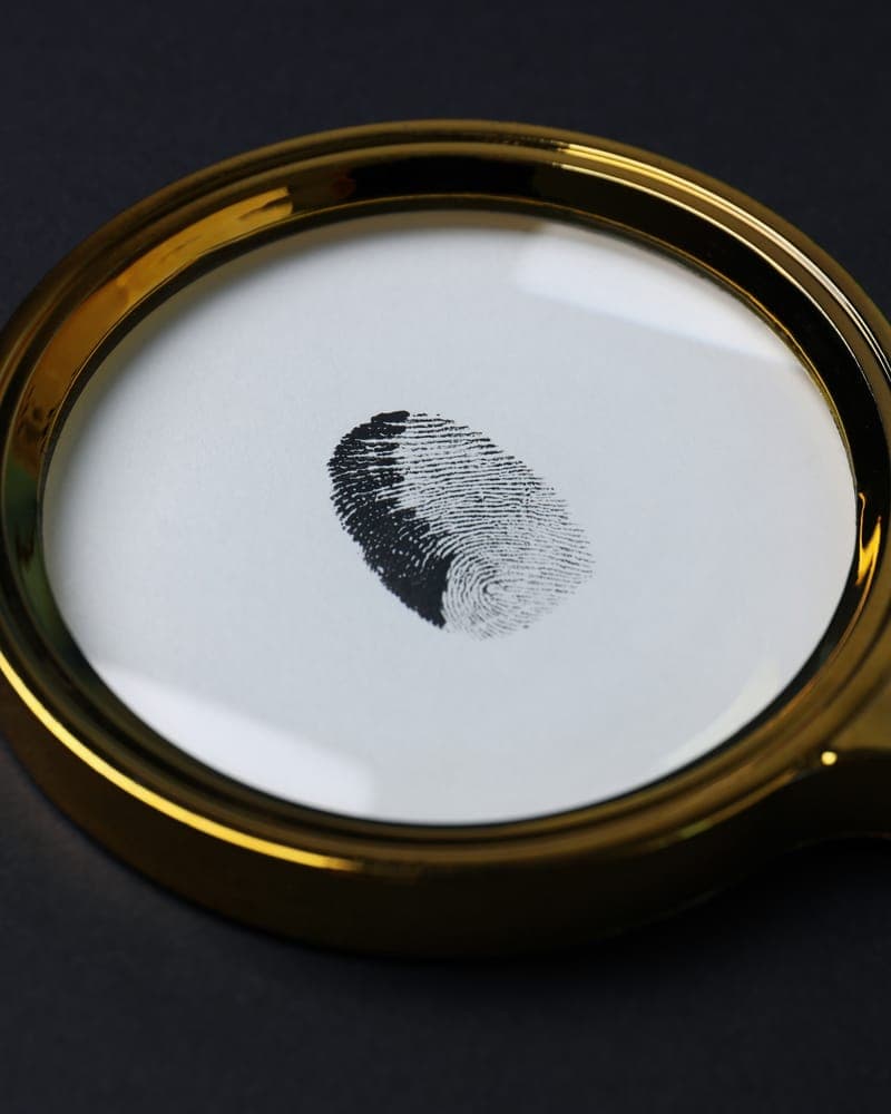 A fingerprint seen through a gold magnifying glass on a dark surface